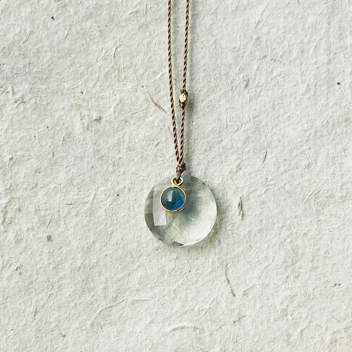 Sapphire and prasiolite necklace on brown cord with circular green stone and small blue stone charm