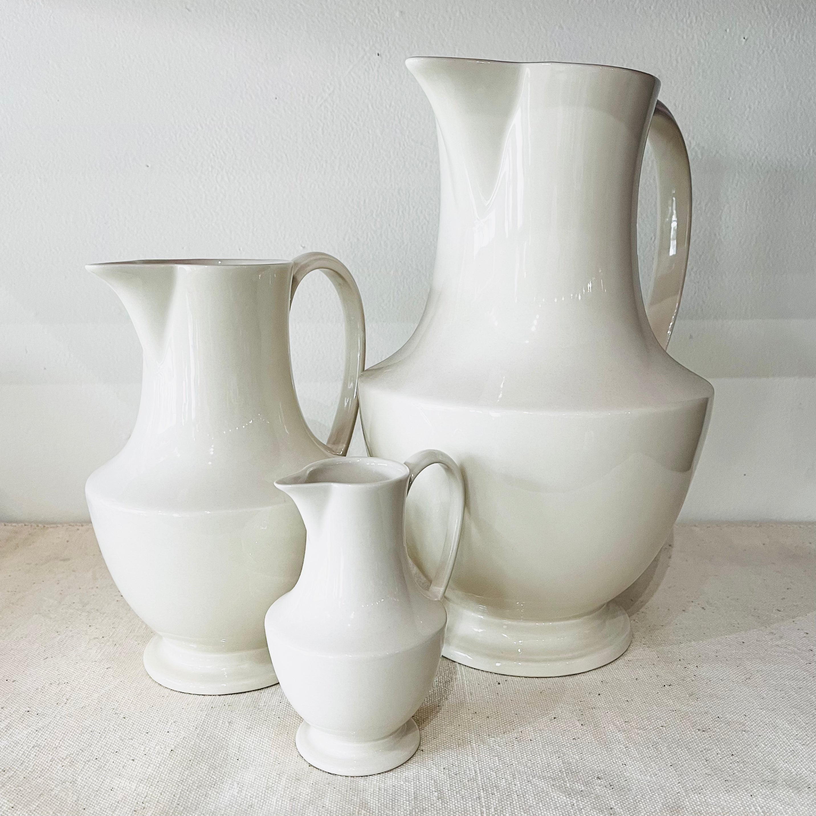 Toulouse medium pitcher displayed with three other white pitchers in graduated sizes