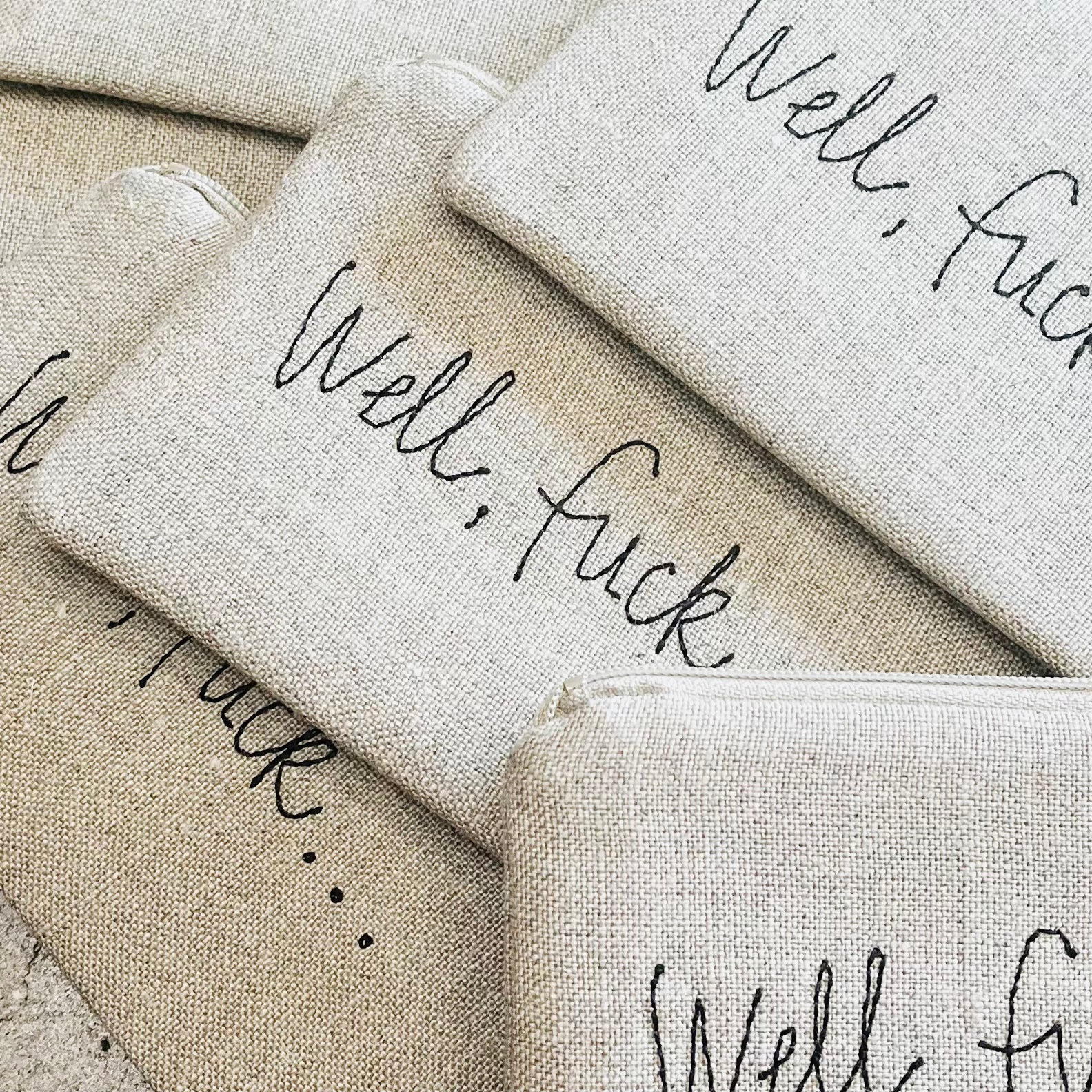 Natural linen pouches with black embroidered text reading well fuck and well