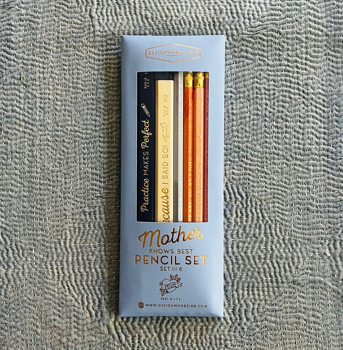 Mother Knows Best pencil set in light blue packaging with six pencils in black, gold, and orange