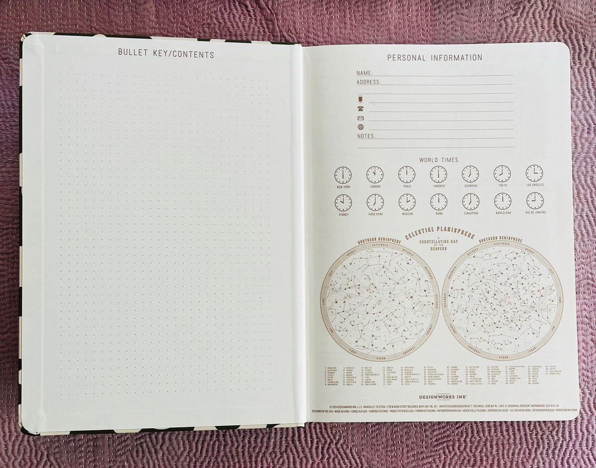 Open journal showing dotted bullet key page and personal information page with celestial maps