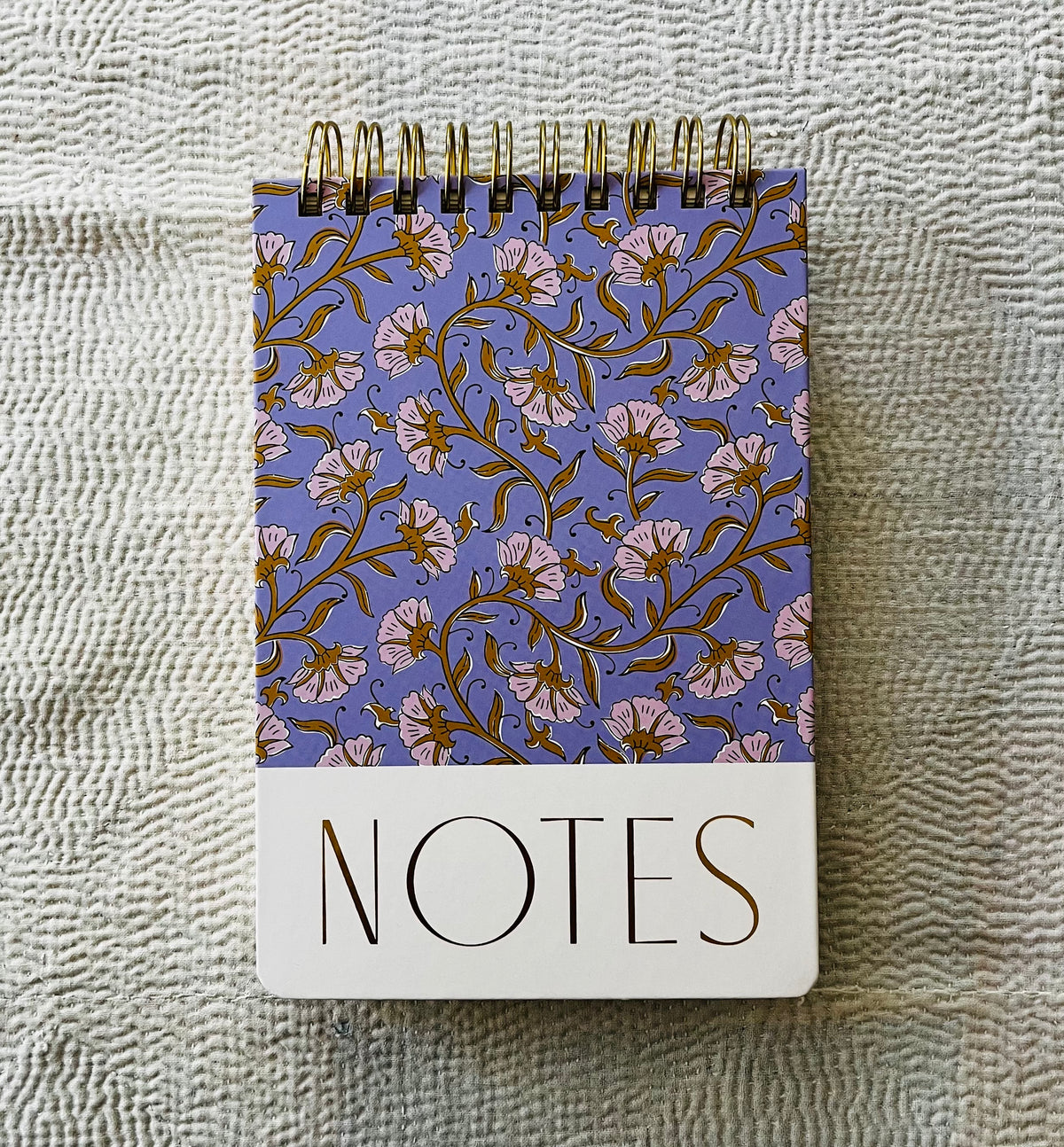 Spiral-bound notepad with purple floral pattern and cream bottom section labeled NOTES