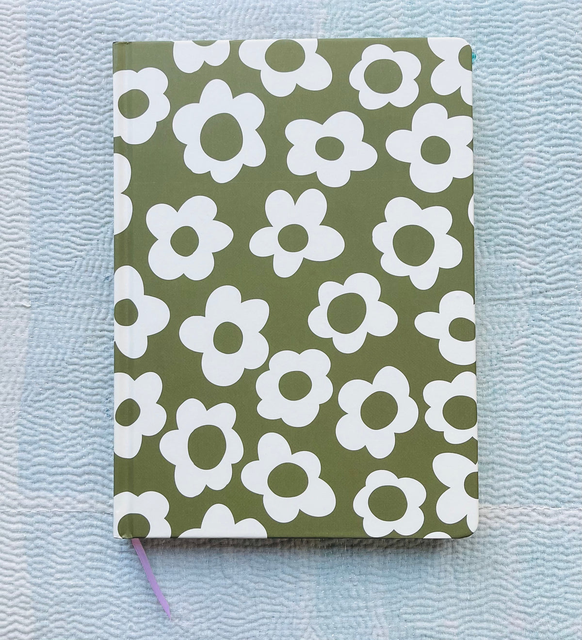 Green journal with white retro flower pattern, purple ribbon bookmark visible at bottom