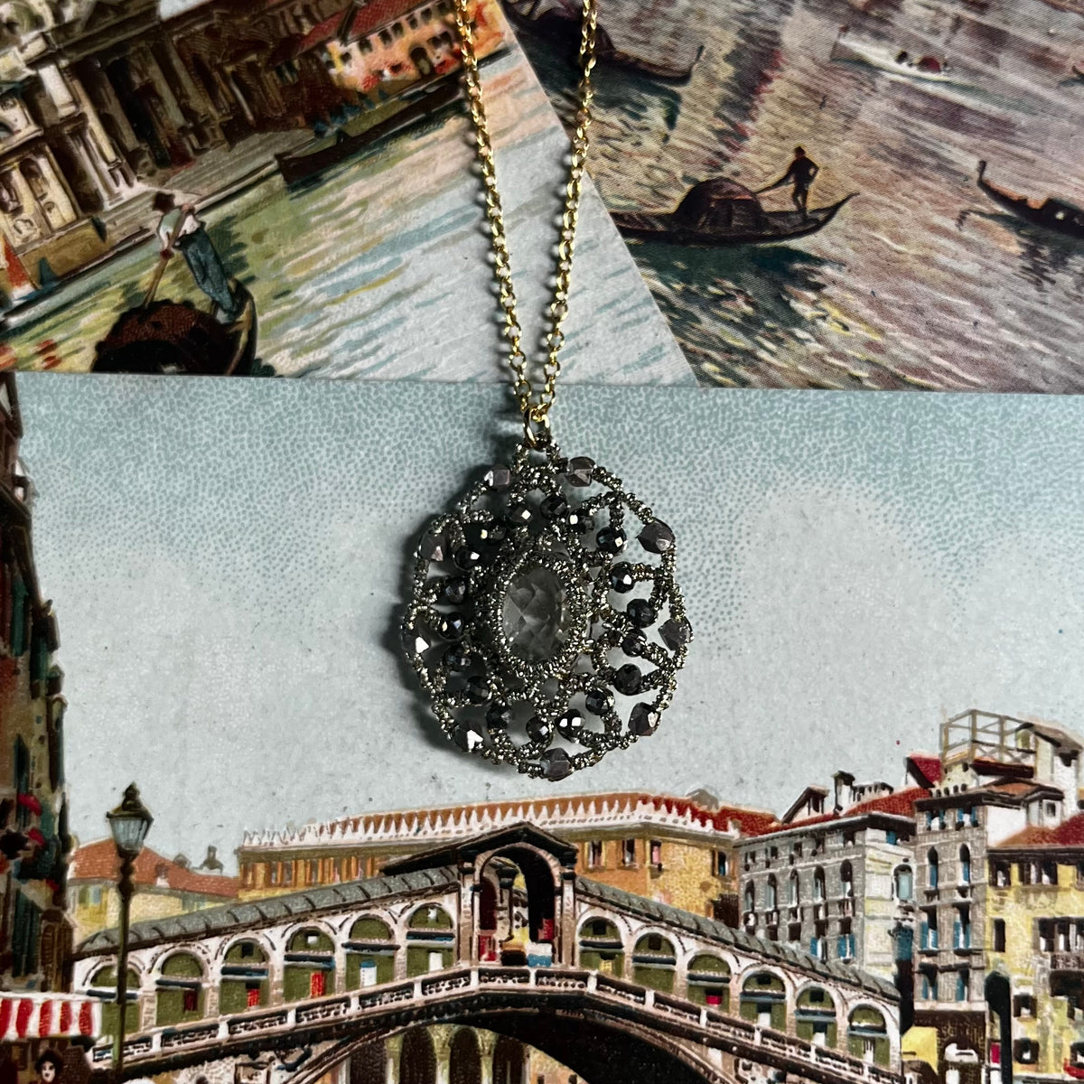 Caught in my Web necklace with black crystals on chain, displayed over Venice artwork