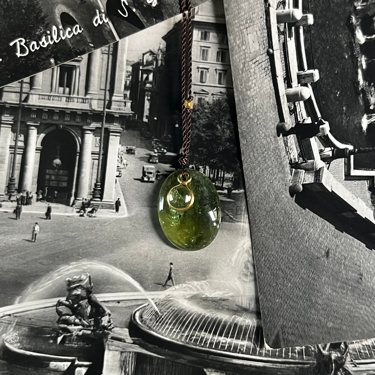 Green tourmaline halo necklace on gold chain displayed against vintage black and white postcard