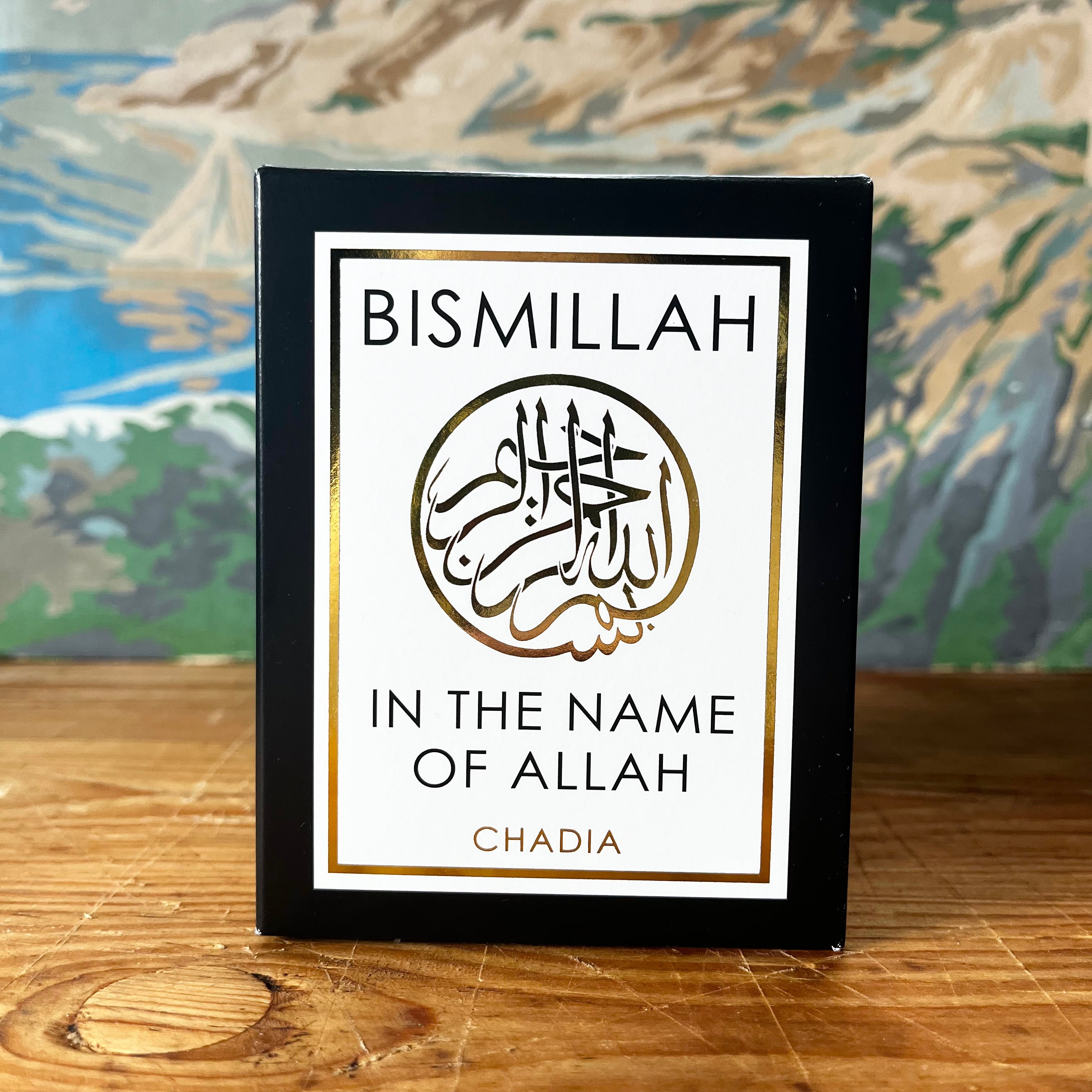 Black framed Bismillah candle with Arabic calligraphy and gold border on wooden surface