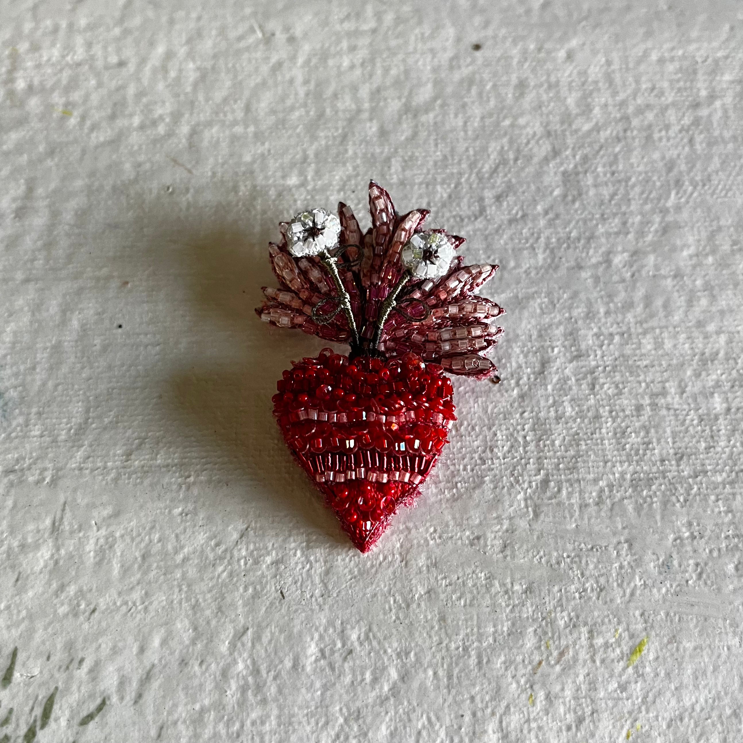Sacred Bloom Brooch with red beaded heart and pink crystal flower on white textured surface