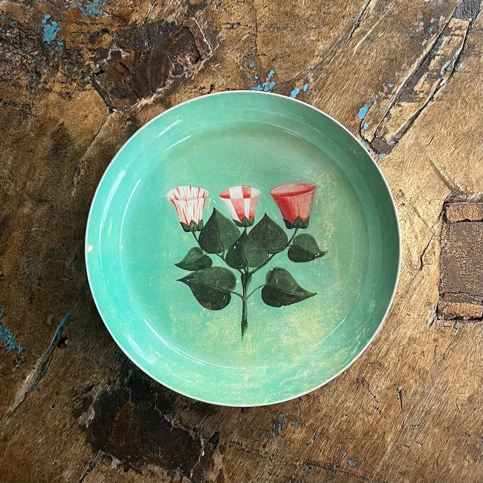 Round turquoise Festival of Flowers tray with painted red and white flowers on distressed wood surface