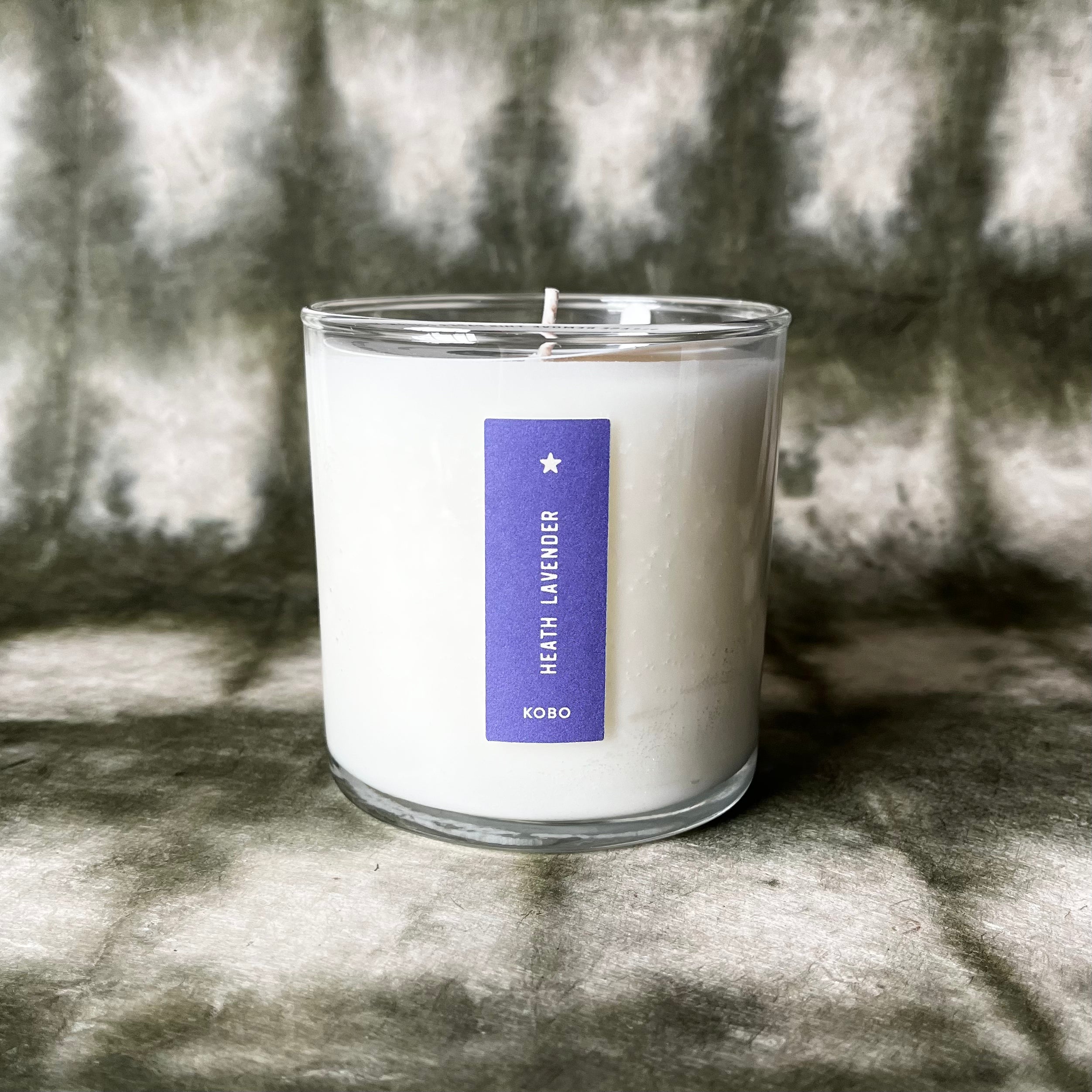 White lavender scented candle in clear glass jar with purple KOBO label
