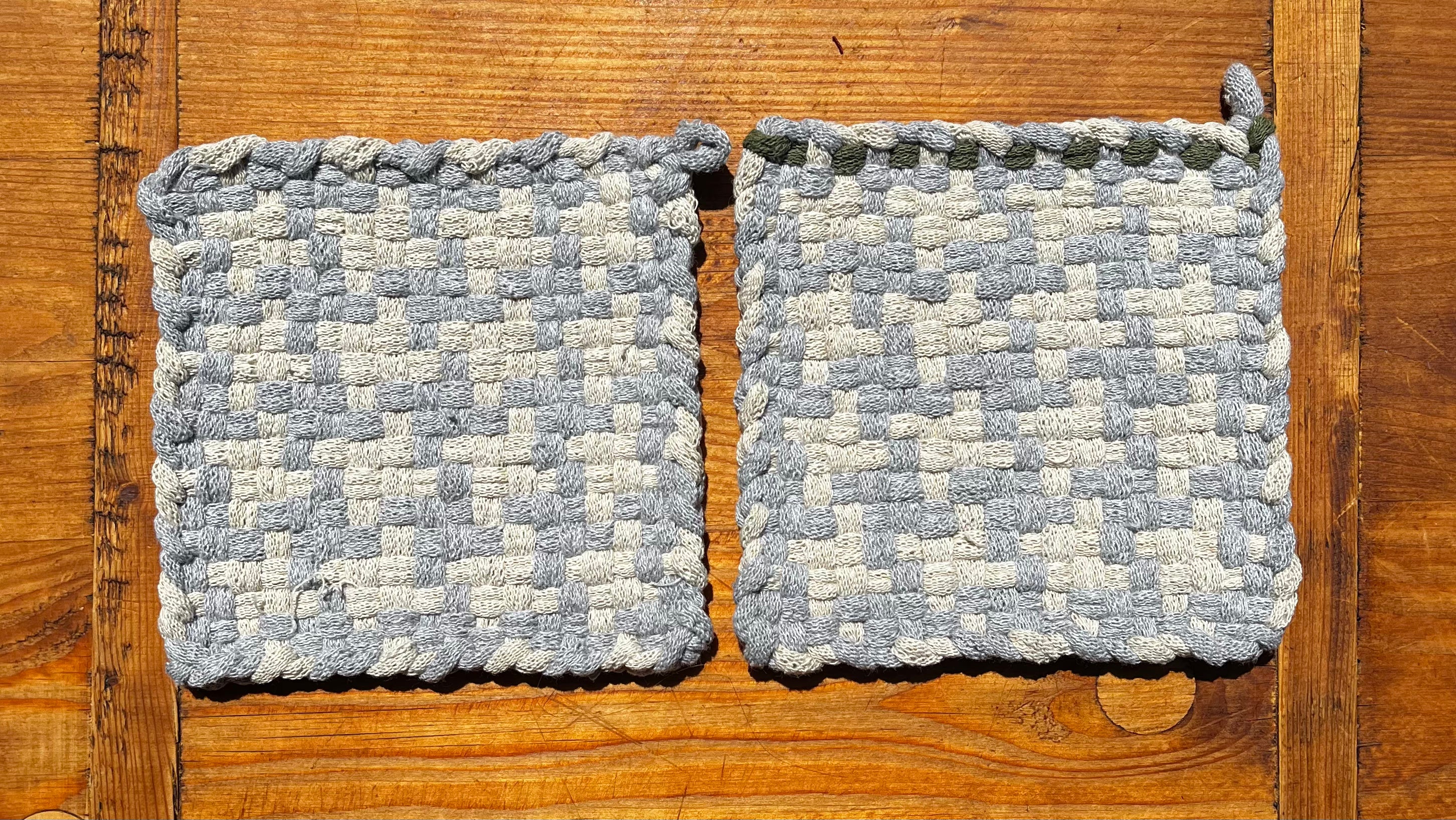 Two gray and cream checkered woven Static Potholders on wooden surface