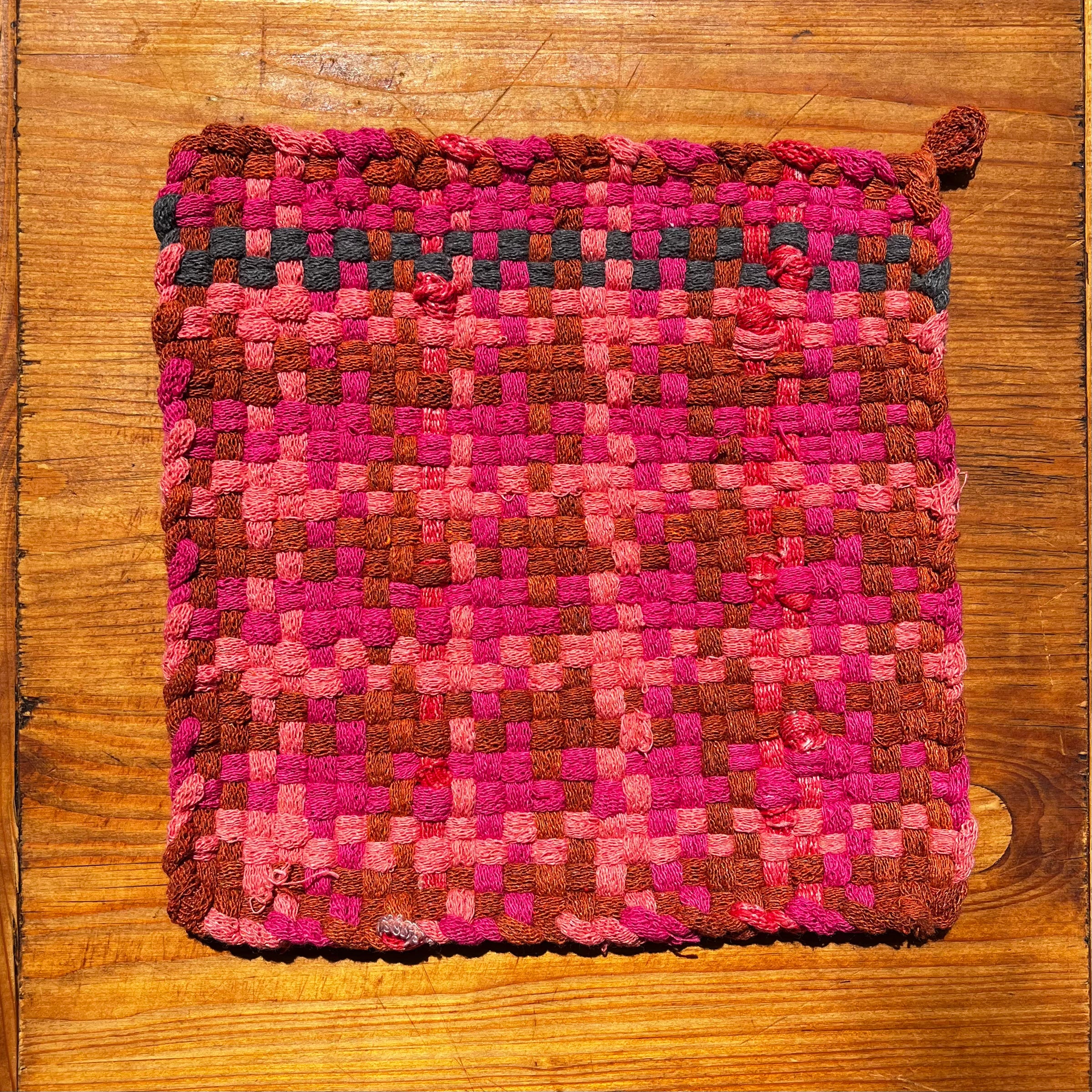 Sweet Sherbet Potholder in pink, brown, and coral woven checkerboard pattern on wooden surface