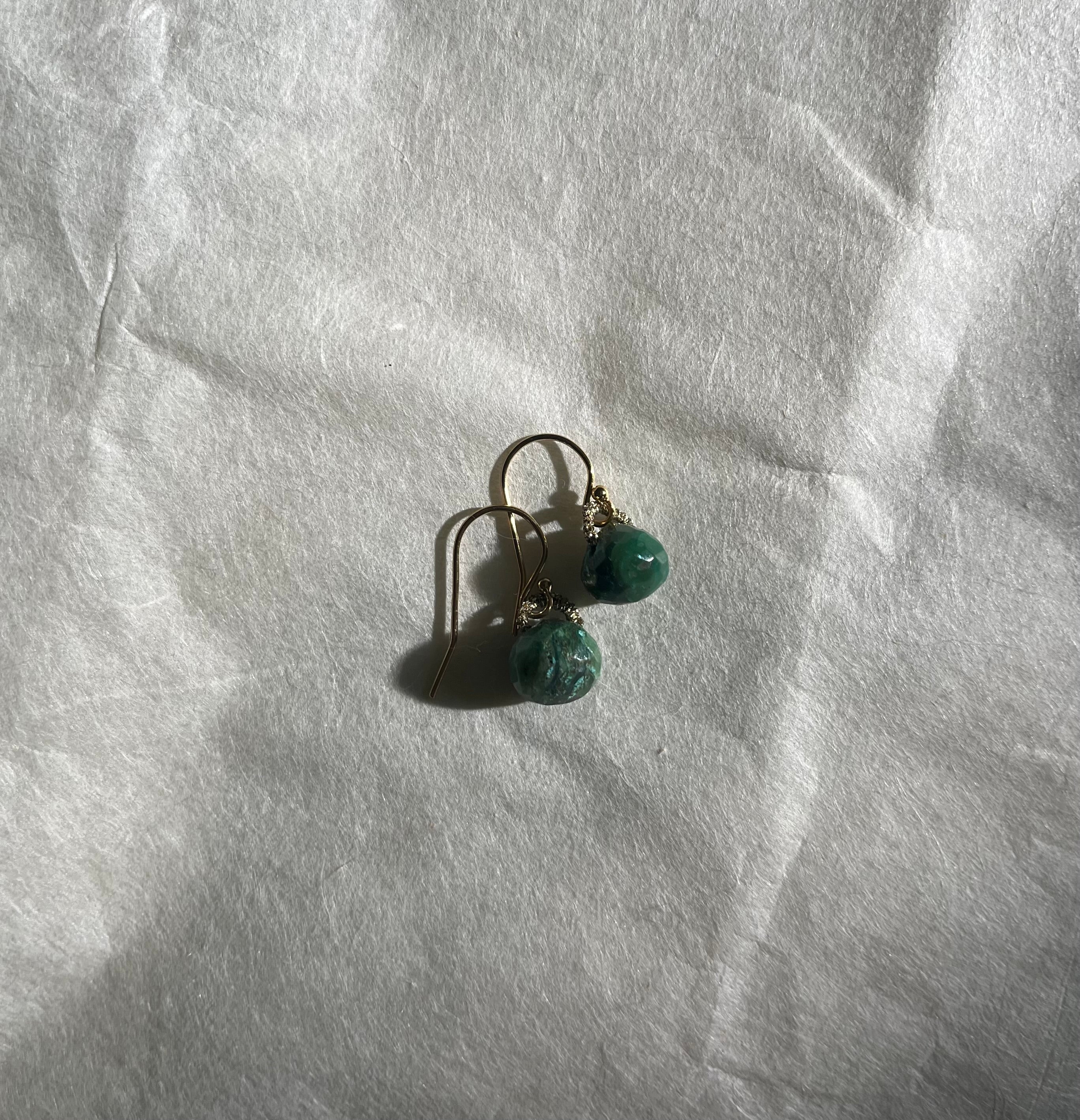 Peruvian opal earrings with pyrite accents on silver hooks against white fabric