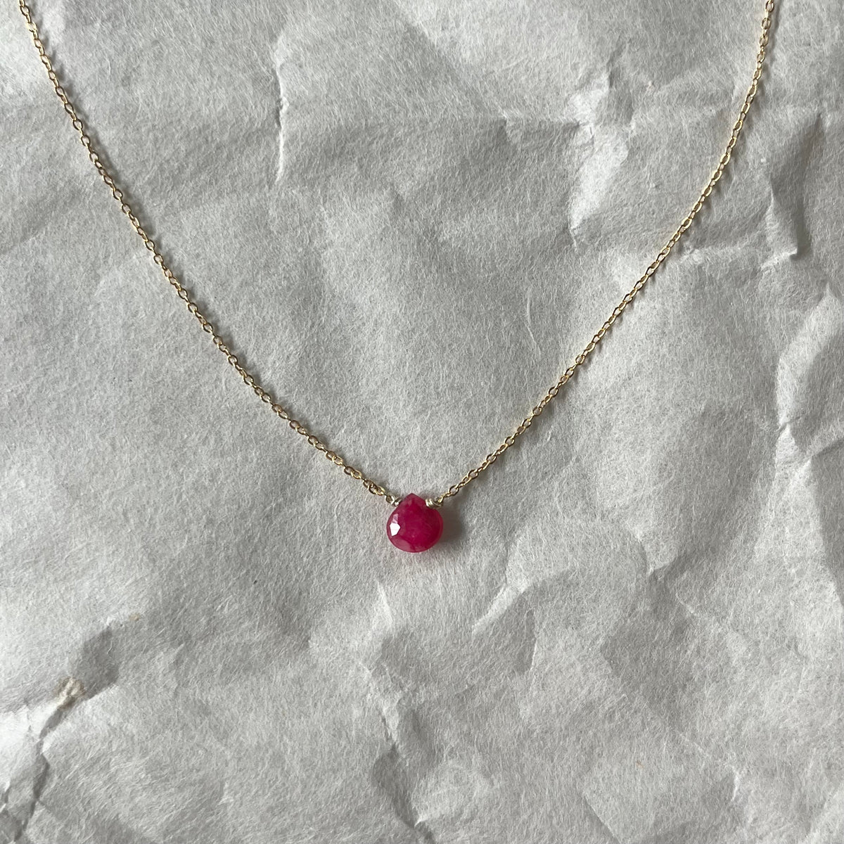 Faceted ruby necklace with single deep pink gemstone pendant on delicate gold chain