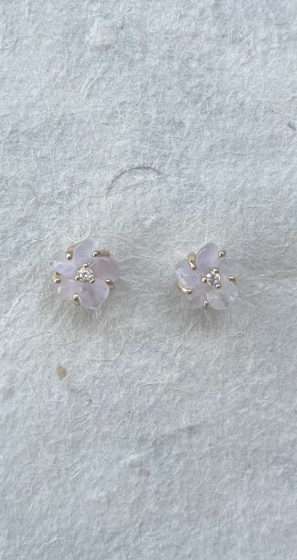 Rose quartz and CZ flower stud earrings on light gray textured surface
