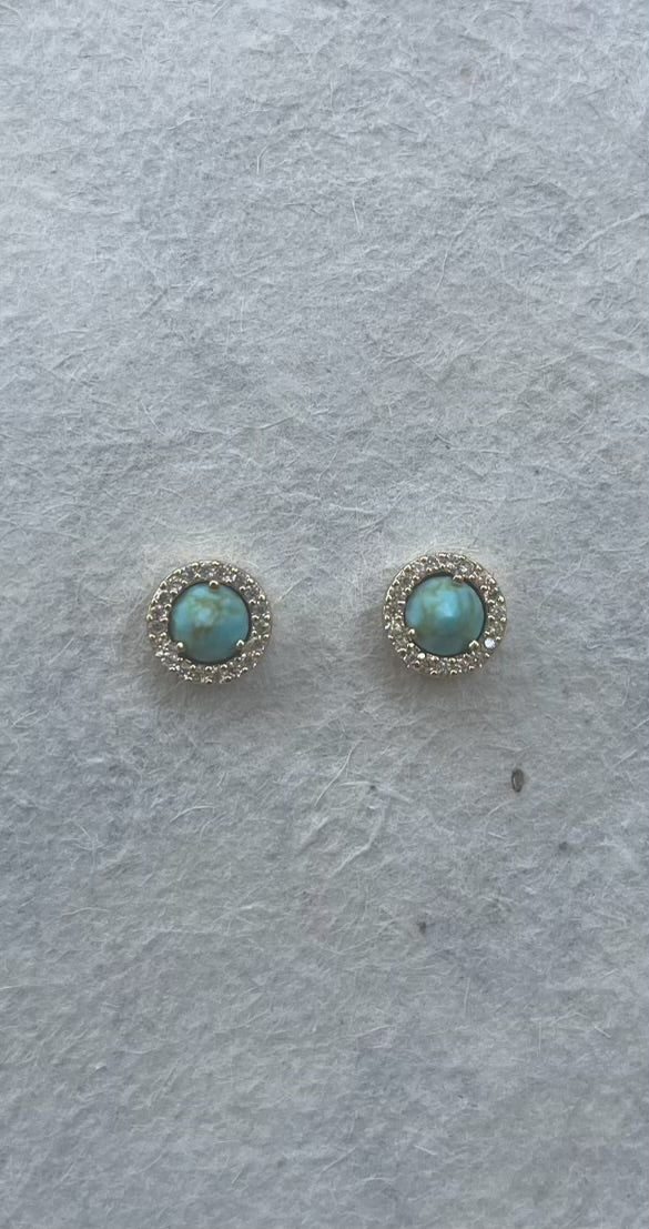 Pair of round turquoise stud earrings with CZ halo on gray background