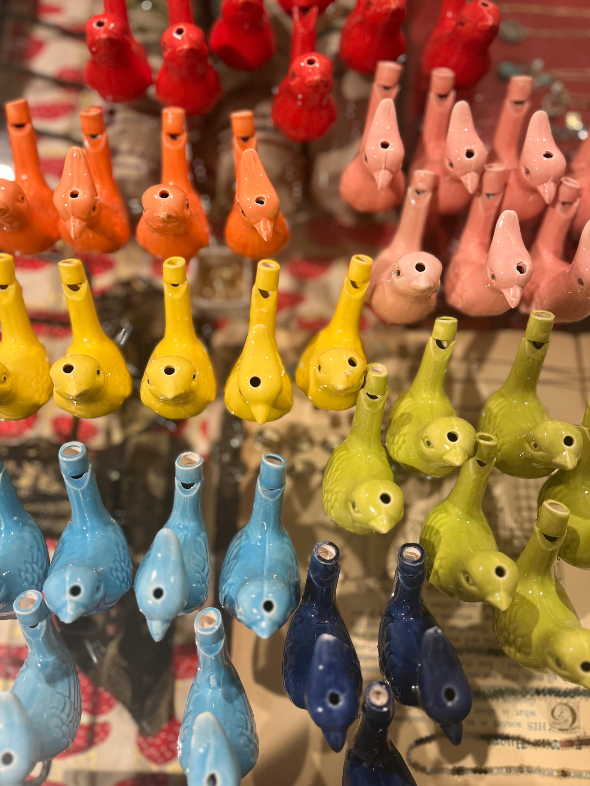 Colorful ceramic water bird whistles arranged in rows by color from red to blue