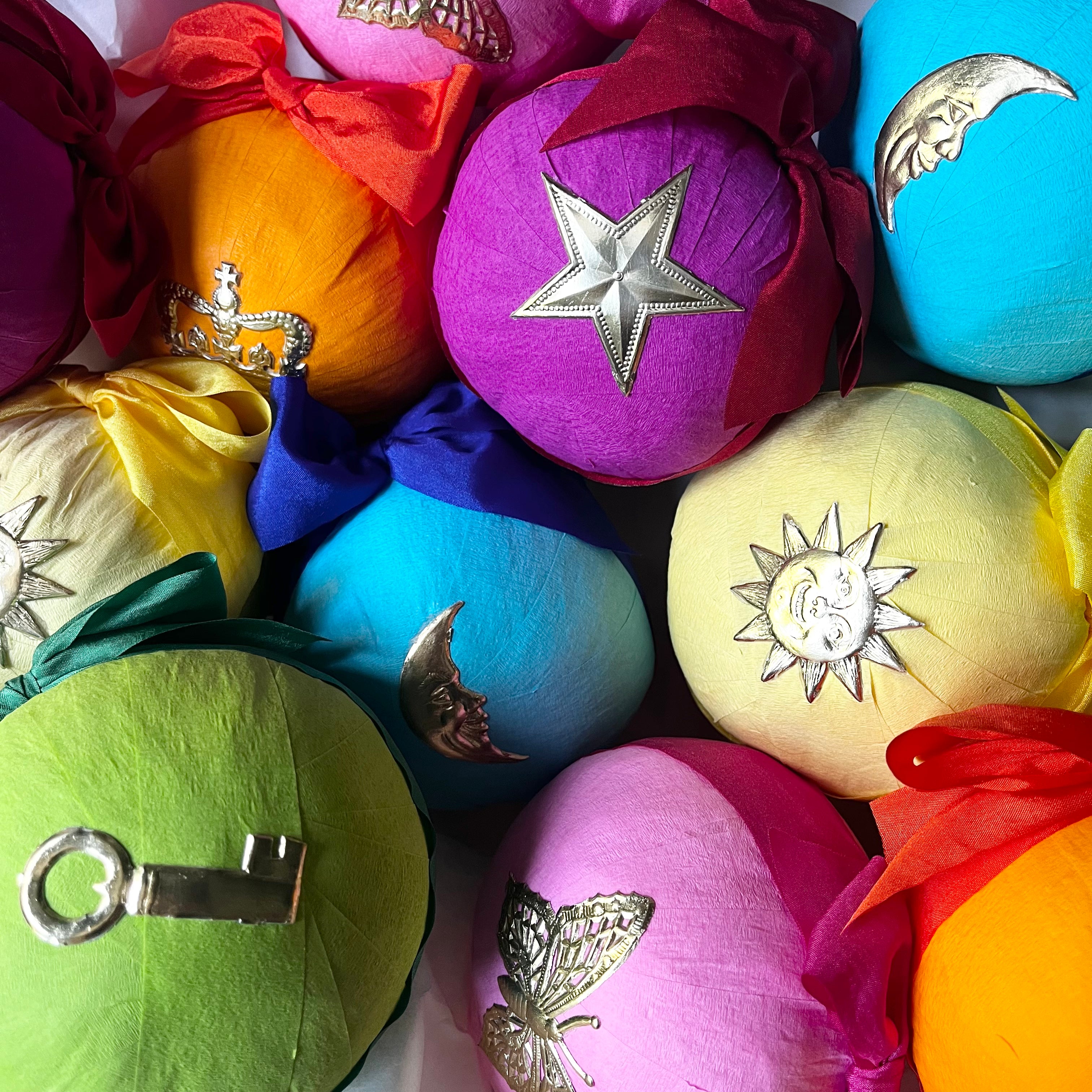 Colorful crepe paper wrapped surprise balls decorated with silver star, sun, moon, key, and butterfly charms