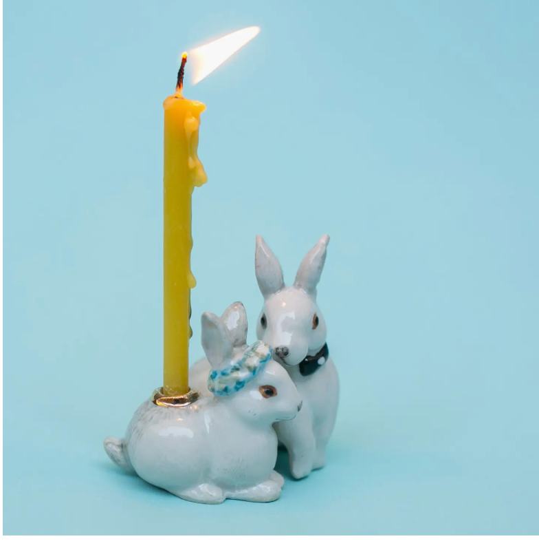 White ceramic rabbit wedding cake topper with yellow candle and two bunny figurines